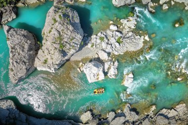 White water Rafting Adventures:  A yellow Raft Floating among the rocks on the Crystal Clear, blue-green water of Vjose river, Albania. Perpendicular drone view of the rafters floating on river. 
