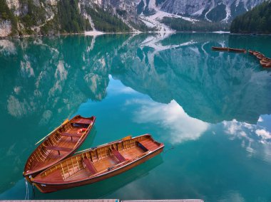 Dolomite tepelerini yansıtan Lago di Braies 'in mavi-yeşil su yüzeyinde iki ahşap tekne. Poster projeleri için ideal.
