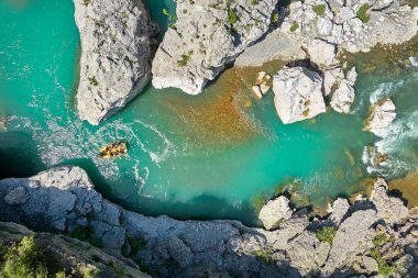 Beyaz su raftingi. Macera ve spor. Sarı bir sal kristal berraklığında kayaların arasında süzülüyor, mavi-yeşil su. Arnavutluk 'un Vjose Nehri üzerinde yüzen kirişlerin dikey drone görüntüsü.