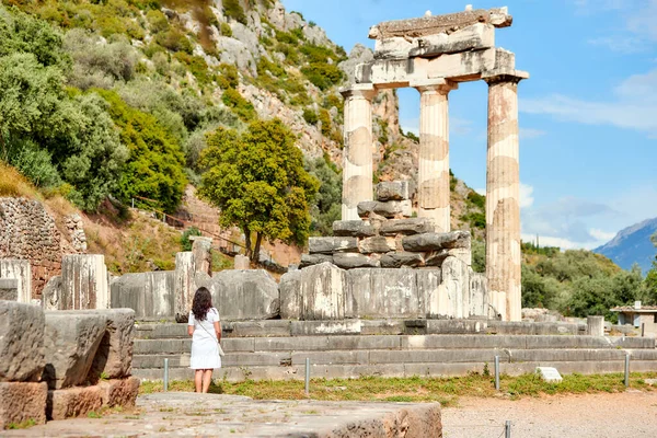 デルファイのアテナ プロナイアの古代神殿複合体を見ている白いドレスの長い髪の女性 晴れた日 ユネスコ世界遺産 デルファイ ギリシャ ストック写真