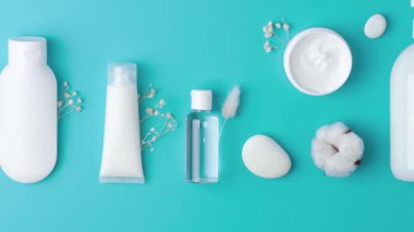 Kozmetik kompozisyon, kozmetik cilt bakım ürünleri ve mavi arka planda çiçekler. Düz yat, boşluğu kopyala 