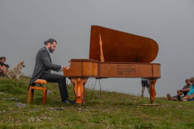 Bergamo Italy August 7, 2024: Pianist performs in the mountains to raise awareness of respect for nature clipart