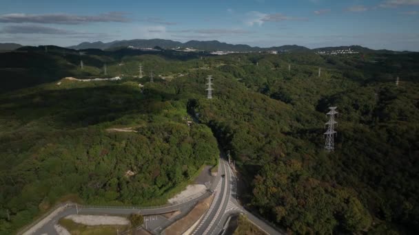 緑の丘陵や高電圧塔を介してカーブ道路上の軽交通 高品質4K映像 — ストック動画