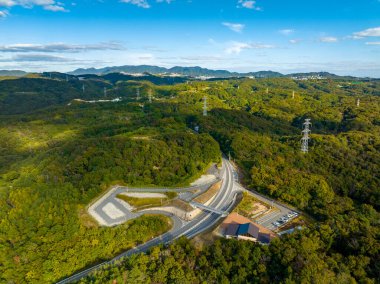 Yeşil kıvrımlı tepeler ve yüksek voltaj kuleleri boyunca uzanan boş yol. Yüksek kalite fotoğraf