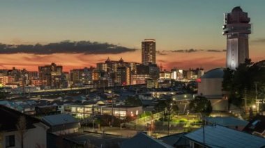 Gün batımında trenler geçerken bulutlar küçük şehir ve saat kulesinin üzerinden geçiyor. Yüksek kalite 4k görüntü