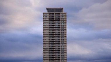 Gün batımında lüks apartman kulesinin üzerinden hızla geçen bulutlar. Yüksek kalite 4k görüntü