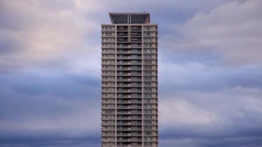 Gün batımında lüks apartman kulesinin üzerinden hızla geçen bulutlar. Yüksek kalite 4k görüntü