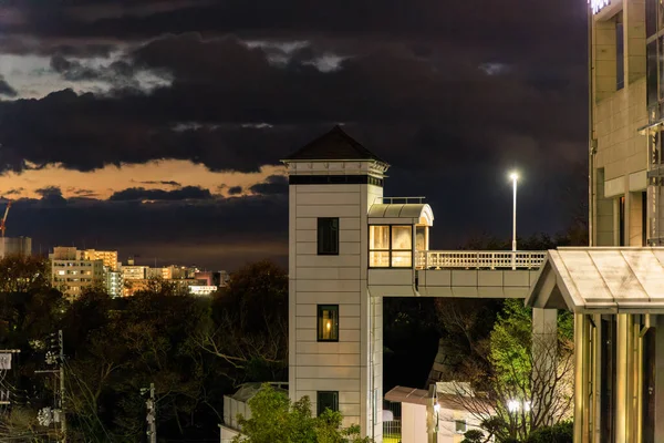 Exterior elevator shaft provides access to public building with dramatic clouds after sunset. High quality photo