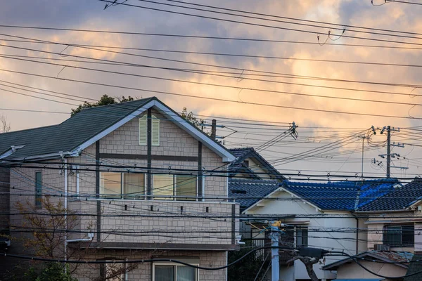 Electrical wires cross suburban homes with sunrise color in clouds. High quality photo
