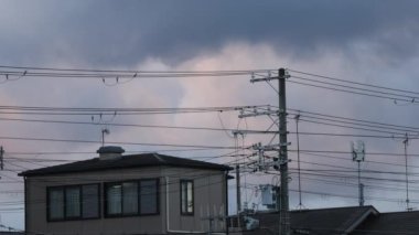 Bulutlar şafak vakti elektrik tellerinden oluşan ağın arkasındaki banliyö evinin üzerinden geçiyor. Yüksek kalite 4k görüntü