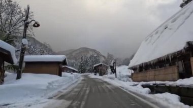 Karlı bir günde, geleneksel bir Japon köyü ve UNESCO dünya mirası alanı olan Shirakawa-go yakınlarındaki dağlarda dar bir yol. Yüksek kalite 4k görüntü