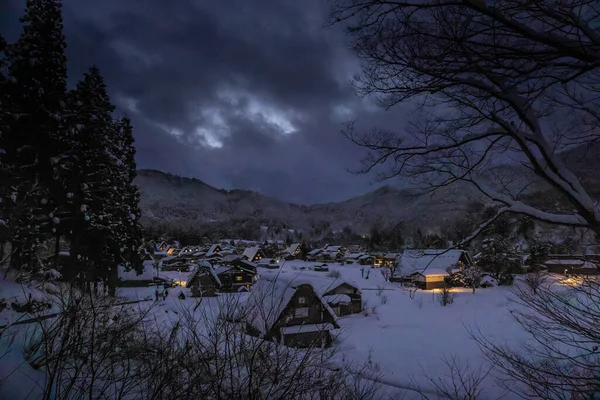 Lights from houses in traditional farming village in snowy valley at dusk. High quality photo
