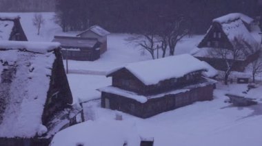Gri şafakta Gokayama köyünün sarp çatılarına kar yağar. Yüksek kalite 4k görüntü