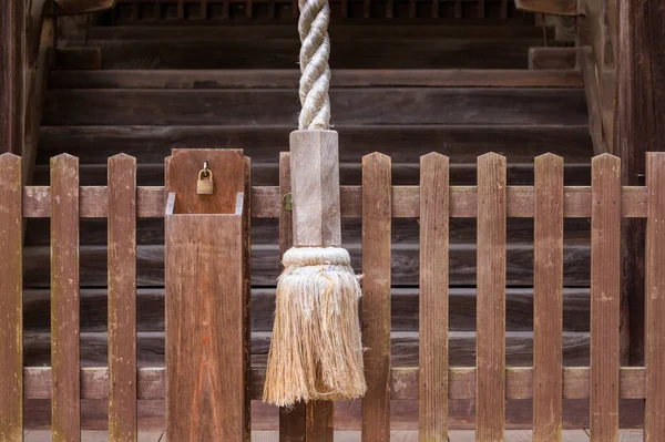 Large rope to ring bell at Japanese temple and small padlock on wooden fence. High quality photo