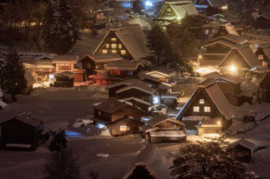 Colorful lights from small mountain village in snowy winter landscape at night. High quality photo