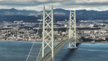 Light Traffic on Akashi Kaikyo Suspension Bridge with Coastal City and Mountains. High quality 4k footage