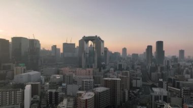 Osaka, Japan - January 7, 2023: Rising up over Umeda Sky Building in haze at sunrise. High quality 4k footage