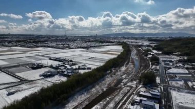 Rare snow on suburban houses by rice fields with Akashi Bridge and Awaji Island in distance. High quality 4k footage