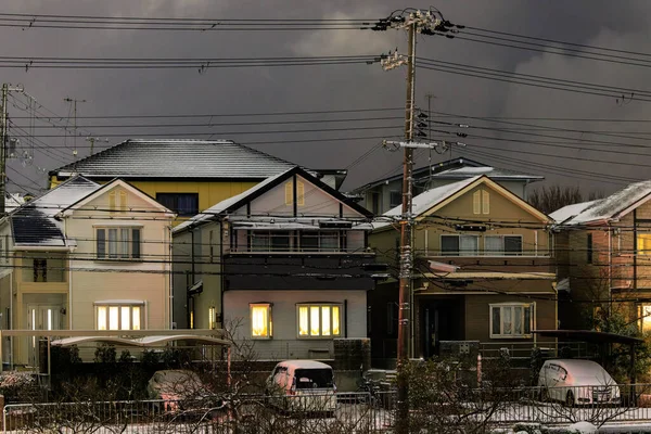 Light dusting of snow on suburban houses with lights on at night. High quality photo