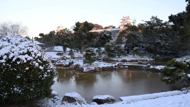 Dawn Light Hits Japanese Castle Tower Overlooking Pond Snow Covered — стоковое видео