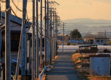 Electrical poles and overhead wiring over narrow neighborhood road at sunset. High quality photo