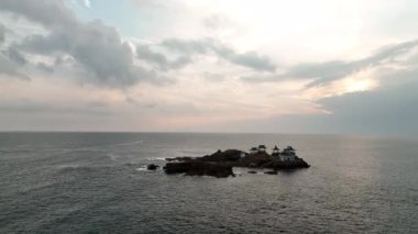Slow low rotate around shrine on rocky island at sunrise. High quality 4k footage