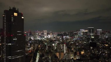 Lights from modern city buildings hit clouds overhead at night. High quality 4k footage