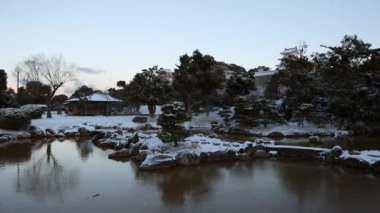 Partially frozen pond in snow covered Japanese garden at dawn. High quality 4k footage