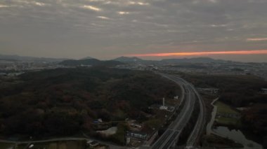 Flying over curved road toward distant hills with predawn color in sky. High quality 4k footage