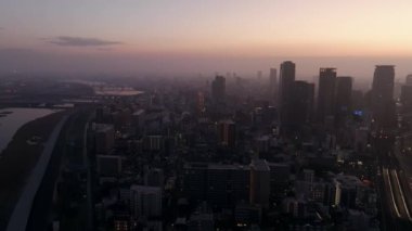 Gündoğumunda sisli bir şekilde yayılan modern şehir etrafında dönen hava rotasyonu. Yüksek kalite 4k görüntü