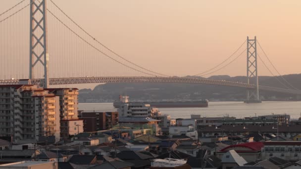 Cargo Ship Sails Suspension Bridge Coastal Town Golden Hour High — Stock video
