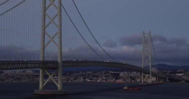 Light from Cars on Akashi Suspension Bridge as Ship Passes Below at Dusk. High quality 4k footage