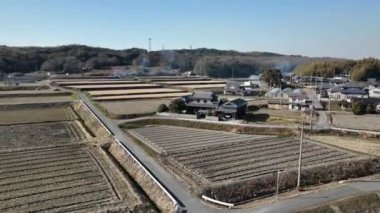 Aerial rotation over traditional Japanese farmhouse by dry fields in winter. High quality 4k footage