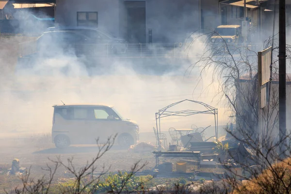 Thick smoke around small car on suburban yard with garden furniture. High quality photo