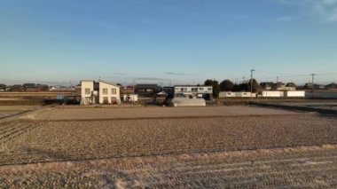 Flying fast and low over dry empty fields by houses in small rural community . High quality 4k footage