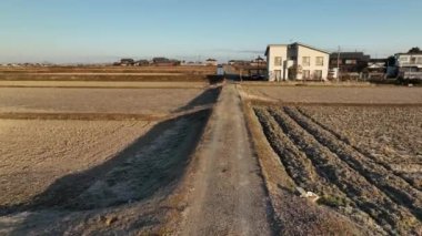Kuru tarlalardan kırsal alandaki büyük modern evlere kadar toprak yolu daralt. Yüksek kalite 4k görüntü