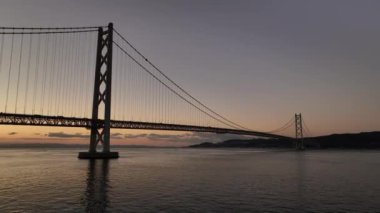 Güneş doğmadan önce sakin suyun üzerindeki asma köprüde alçak gerileme. Yüksek kalite 4k görüntü