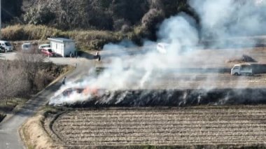 Smoke and flames rise from controlled burn by plowed rows in unplanted field. High quality 4k footage