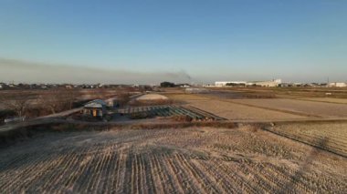 Flying over rustic farm shed by rural fields and river at golden hour. High quality 4k footage