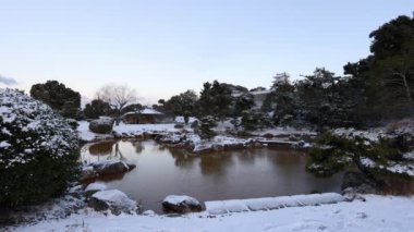 Peaceful view of pond in snowy park and Akashi Castle tower at dawn. High quality 4k footage