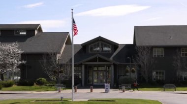 Mill Valley, California - February 22, 2022: Person walks by fluttering American flag and local ballot drop off during election. High quality 4k footage