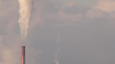 Endüstriyel santraldeki bacalar bulutlu bir atmosfere gaz pompalıyor. Yüksek kalite 4k görüntü