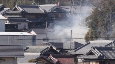 Güneşli bir günde geleneksel ahşap Japon kır evlerinden duman yükselir. Yüksek kalite 4k görüntü