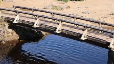 Kuru kumlu çölde akan suyun üzerinde tahta ayak köprüsü. Yüksek kalite 4k görüntü