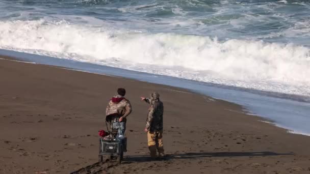 Zwei Fischer Zeigen Auf Wellen Die Strand Brechen Hochwertiges Filmmaterial — Stockvideo