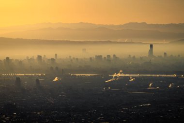 Sabahın erken saatlerinde şehir sisi ve gökyüzünde turuncu parıltılı fabrikalar. Yüksek kalite fotoğraf