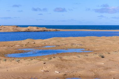 Calm waters of blue lagoon on deserted sandy beach on sunny Point Reyes day. High quality photo clipart