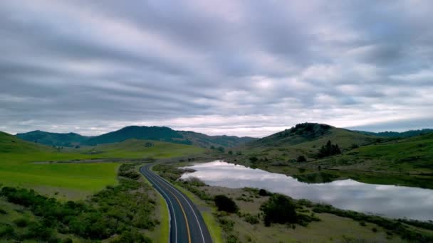 夜明けに緑の丘陵地帯のカリフォルニア貯水池で空の道路を飛んでいます 高品質4K映像 — ストック動画