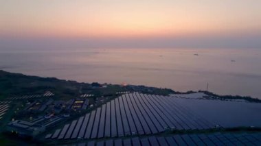 Gün batımında kıyı binalarının yanındaki enerji çiftliğinde güneş panelleri. Yüksek kalite 4k görüntü