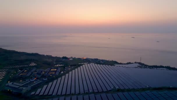 日落时在海滨建筑物旁的能源农场上安装太阳能电池板 高质量的4K镜头 — 图库视频影像